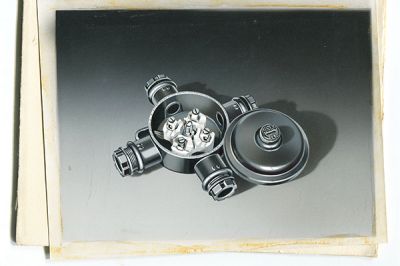 (Ilustración del producto de los años 60. Caja de conexiones redonda de plástico termoestable Duroplast con cuatro entradas de cable y un tornillo de tapa.)